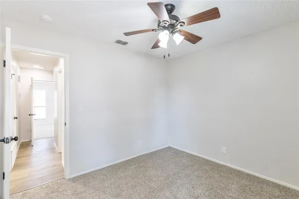 an empty room with a chandelier fan and a ceiling fan