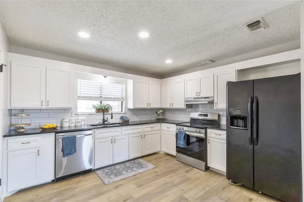 a kitchen with white cabinets stainless steel appliances and sink