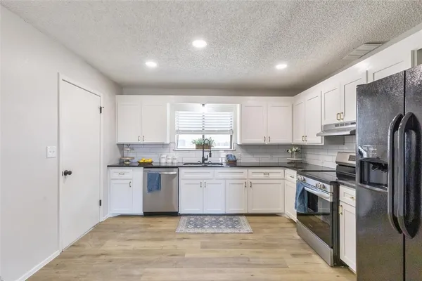 a kitchen with stainless steel appliances granite countertop a stove a sink and a refrigerator