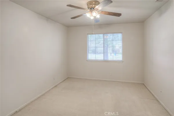 an empty room with a window and a fan