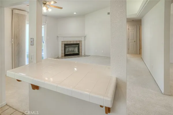 an empty room with kitchen view and a fireplace