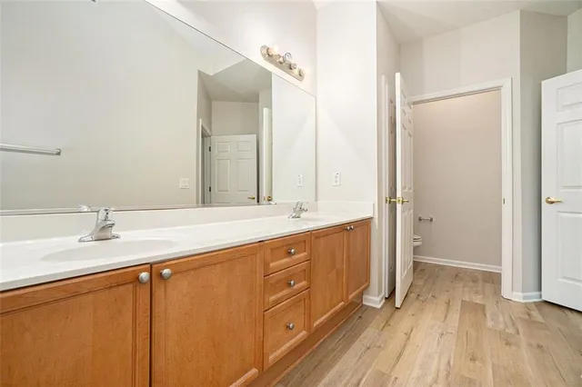 a spacious bathroom with a granite countertop sink toilet a mirror and a shower