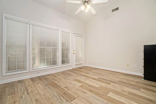 a view of an empty room with a window and wooden floor