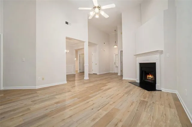 a view of an empty room with wooden floor and a fireplace