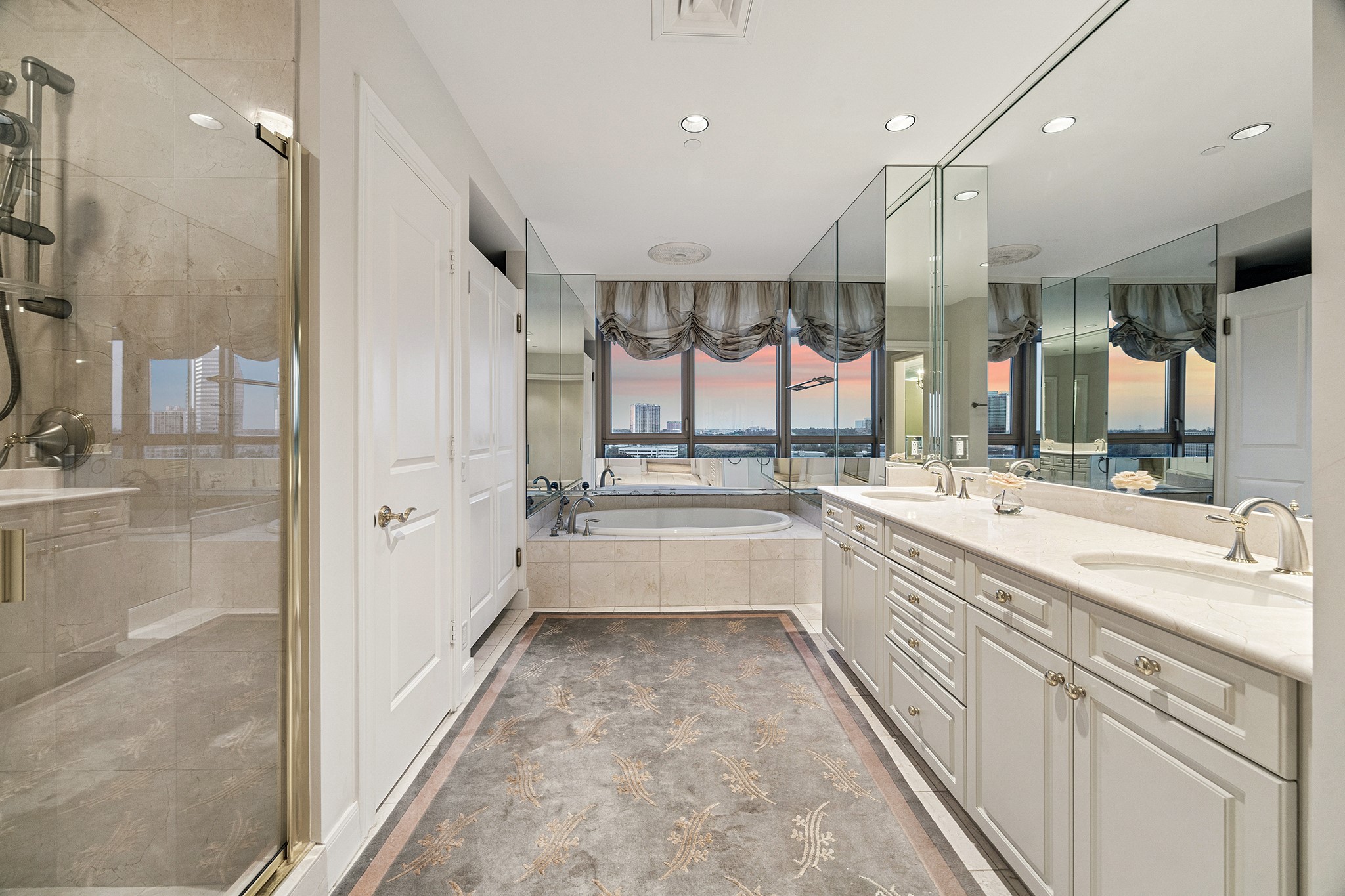 1100 Uptown Park Boulevard, Unit 102 Houston, TX 77056 - Photo 10 of 33 a large white bathroom with a large tub shower sink vanity and a large mirror