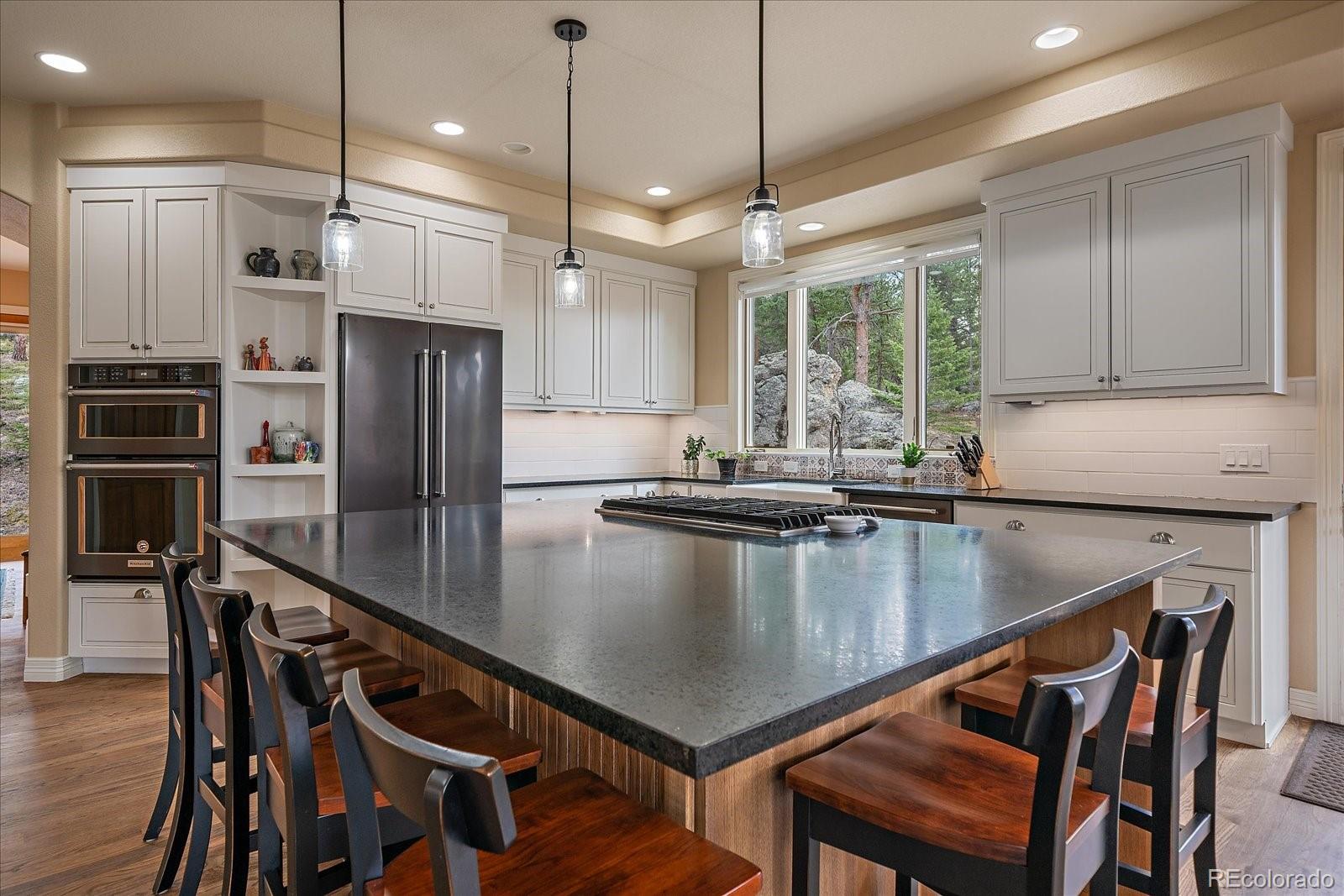 6737 Timbers Drive Evergreen, CO 80439 - Photo 12 of 47 a kitchen with stainless steel appliances granite countertop a stove a refrigerator and a kitchen island