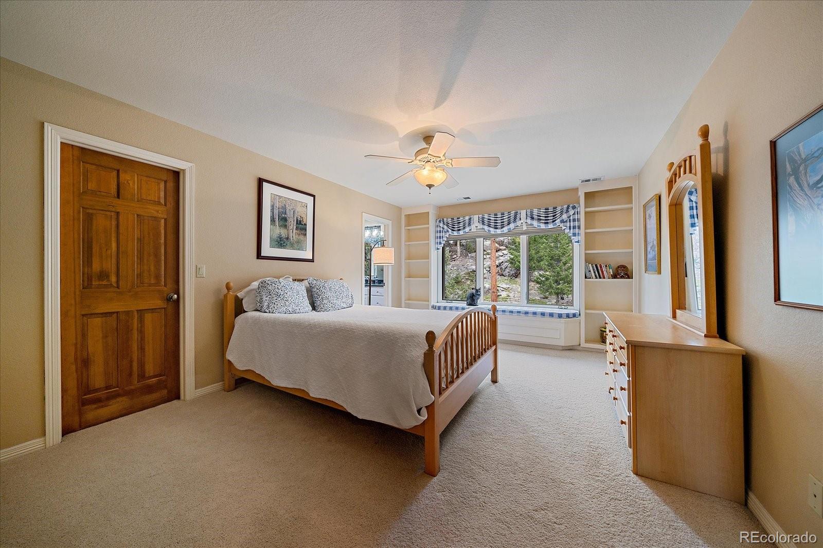6737 Timbers Drive Evergreen, CO 80439 - Photo 31 of 47 a spacious bedroom with a bed and glass window