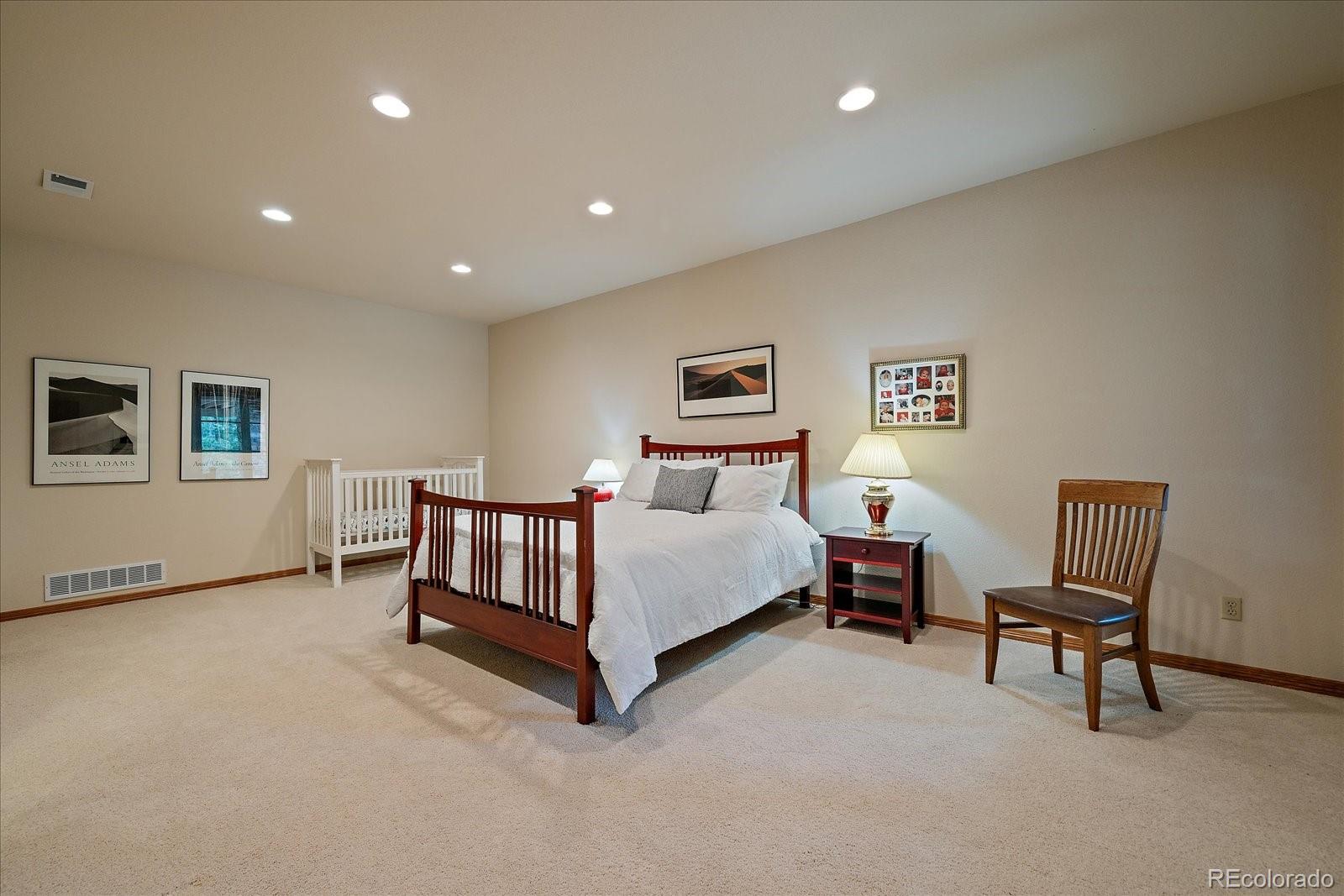 6737 Timbers Drive Evergreen, CO 80439 - Photo 34 of 47 a spacious bedroom with a bed and a chair