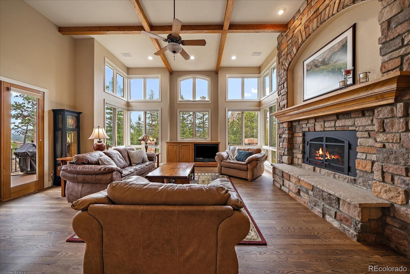 6737 Timbers Drive Evergreen, CO 80439 - Photo 6 of 47 a living room with furniture a large window and a fireplace