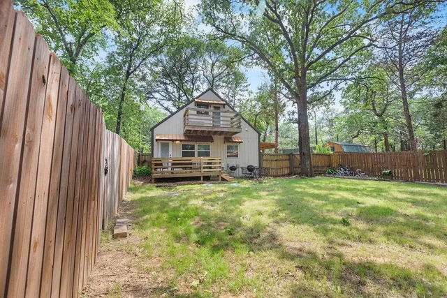 a view of a backyard with large trees and a barn