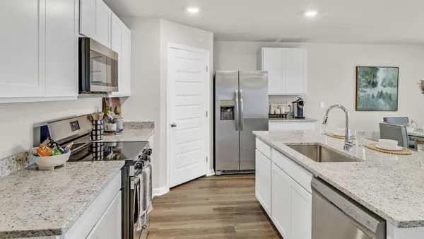 a kitchen with stainless steel appliances granite countertop a dining table chairs refrigerator and microwave