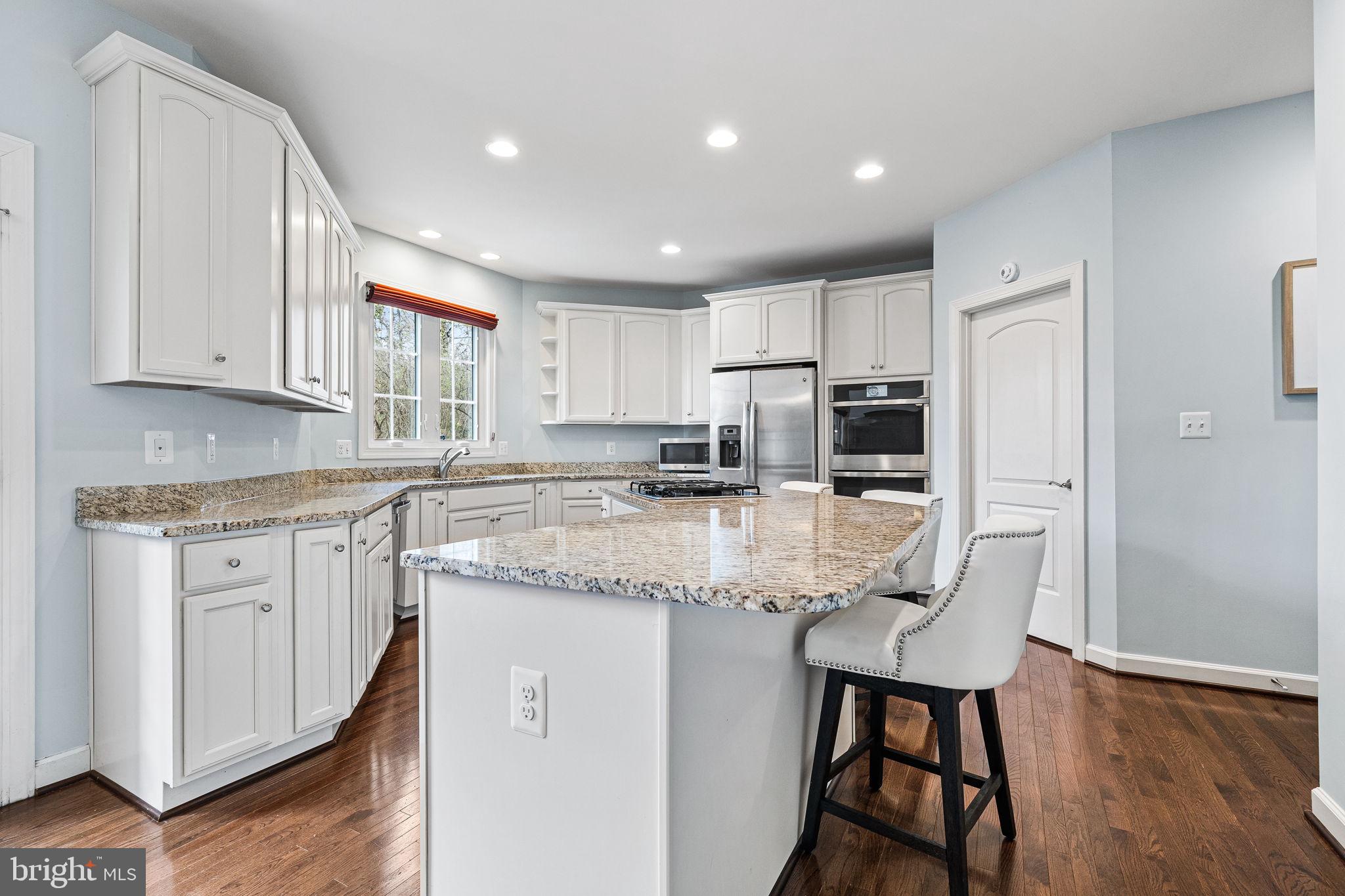 1232 Shenandoah Road Alexandria, VA 22308 - Photo 22 of 50 a kitchen with kitchen island granite countertop wooden floors white cabinets and stainless steel appliances