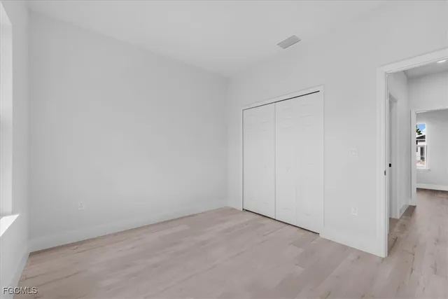 an empty room with wooden floor and a bathroom