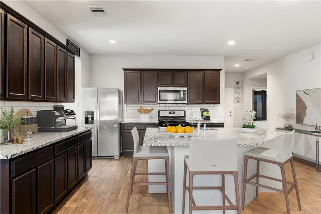 a kitchen with a refrigerator a stove a sink cabinets and a dining table with chairs