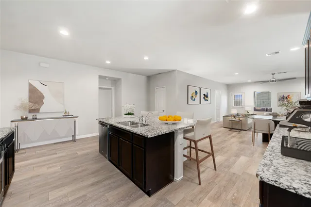 a living room with stainless steel appliances kitchen island granite countertop a sink and a refrigerator