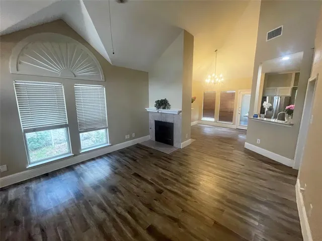 a view of a living room and a kitchen with wooden floor