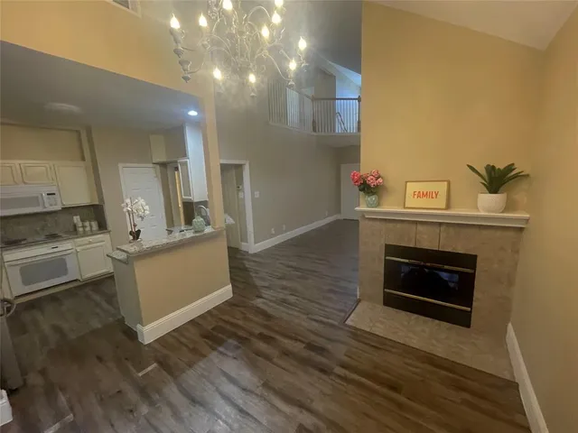 a view of kitchen and empty room with wooden floor