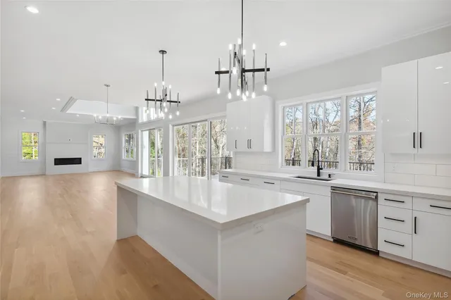a large white kitchen with a large island oven a sink appliances and a chandelier