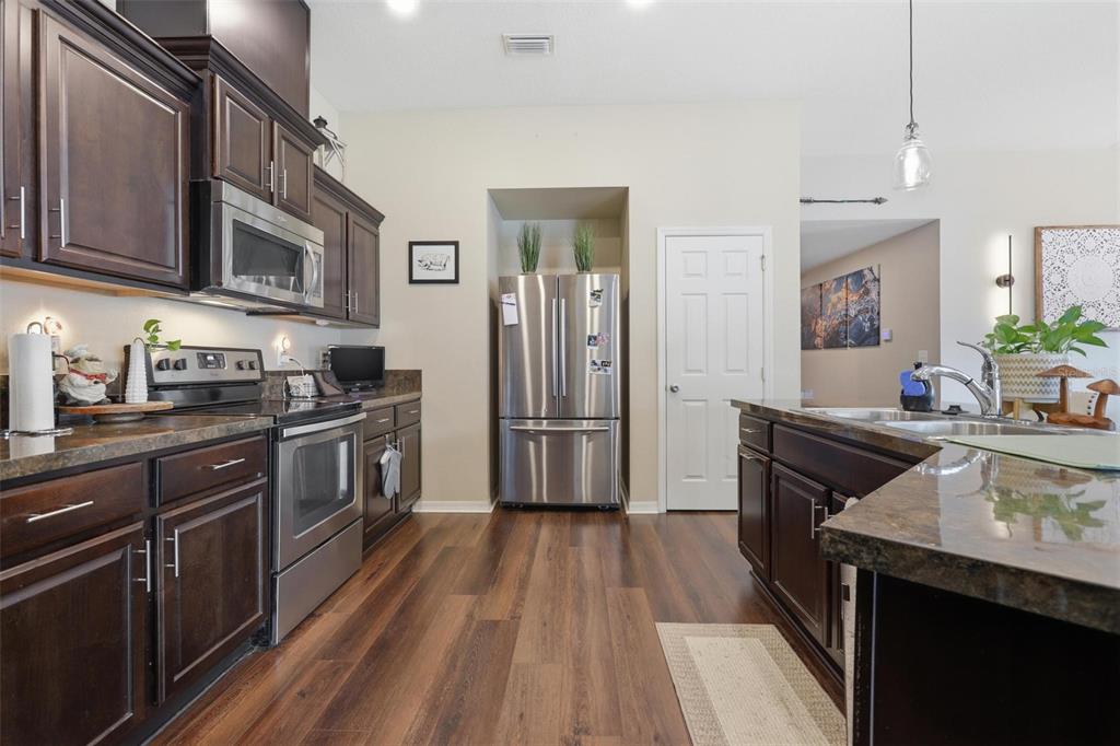 656 Carya Court DeLand, FL 32724 - Photo 9 of 28 a kitchen with stainless steel appliances granite countertop a refrigerator a sink dishwasher a stove and white countertops with wooden floor