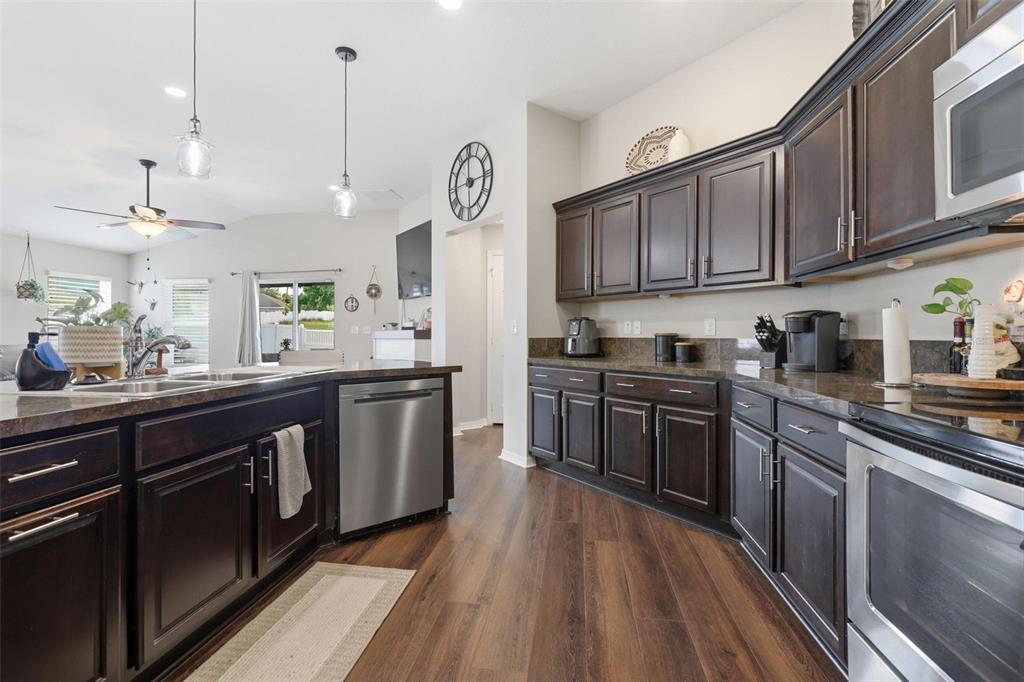 656 Carya Court DeLand, FL 32724 - Photo 10 of 28 a kitchen with stainless steel appliances granite countertop wooden cabinets a stove a sink and dishwasher