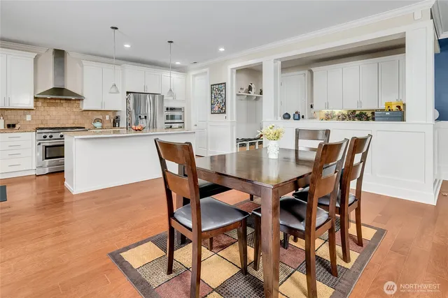 a dining area with stainless steel appliances kitchen island granite countertop a stove a table and chairs