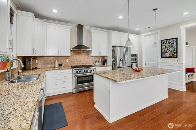 a kitchen with granite countertop a stove top oven a sink dishwasher and a refrigerator with wooden floor