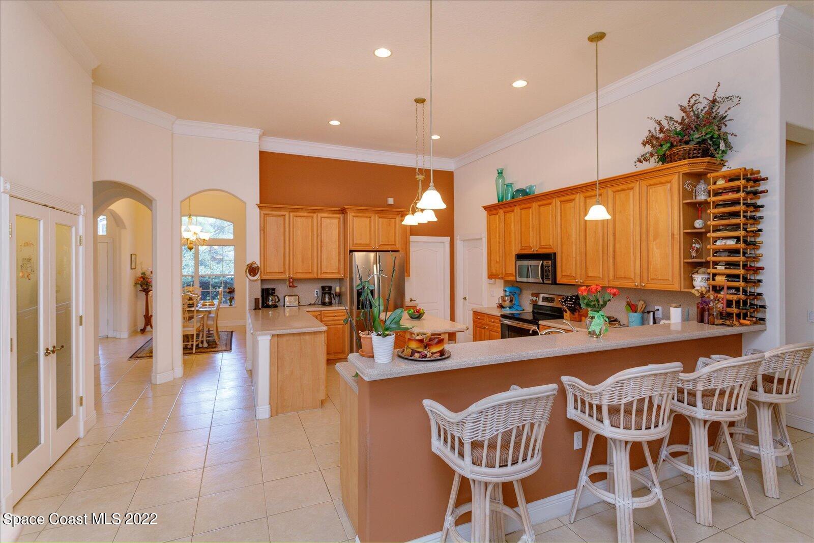 3720 Pine Cone Road Melbourne, FL 32934 - Photo 16 of 34 a view of a dining room with furniture one side kitchen view and chandelier
