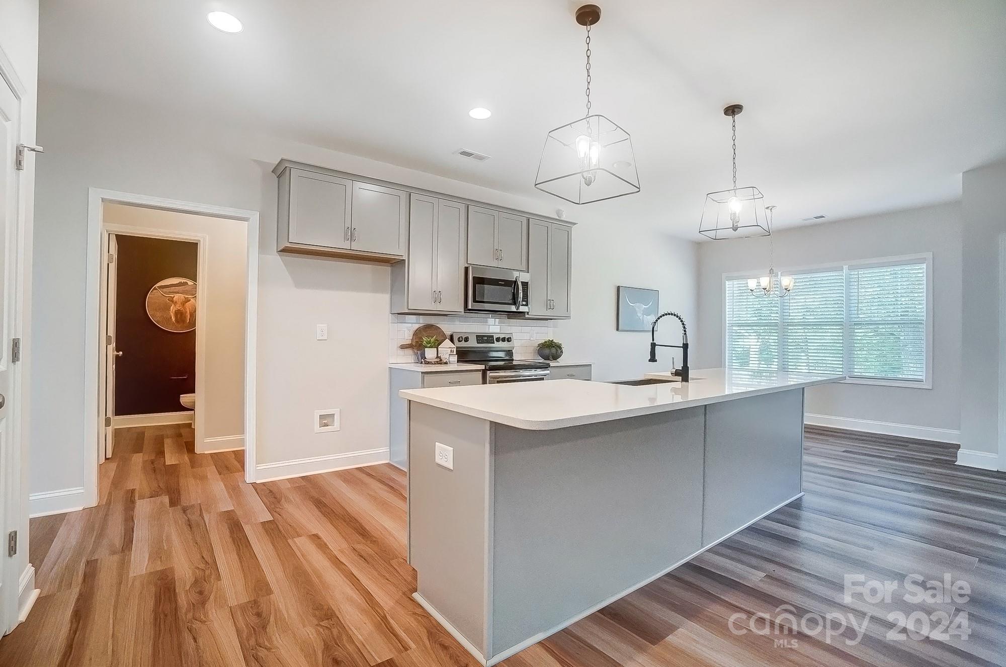 1413 Hamilton Crossroads Road Marshville, NC 28103 - Photo 14 of 42 a kitchen with stainless steel appliances granite countertop a sink dishwasher a refrigerator white cabinets and wooden floor next to a window