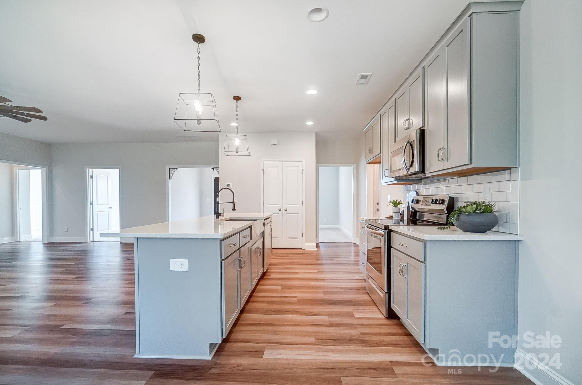 1413 Hamilton Crossroads Road Marshville, NC 28103 - Photo 17 of 42 a large kitchen with stainless steel appliances granite countertop a stove oven a sink dishwasher and white cabinets with wooden floor
