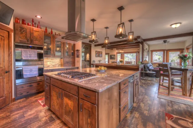a kitchen with stainless steel appliances granite countertop a stove and a view of living room