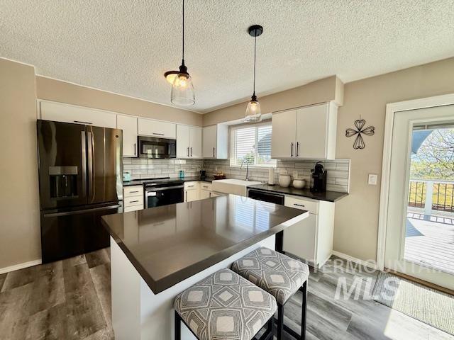2945 25th Street Clarkston, WA 99403 - Photo 27 of 46 Kitchen featuring stainless steel appliances, dark countertops, dark wood-style flooring, a kitchen breakfast bar, and a textured ceiling