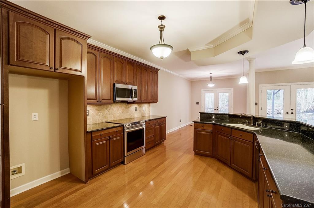 7064 Harbor Court Tega Cay, SC 29708 - Photo 11 of 48 a large kitchen with stainless steel appliances granite countertop a stove a sink dishwasher and a refrigerator with wooden floor