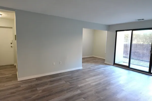 a view of an empty room with wooden floor and a window