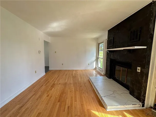 a view of empty room with a fireplace and wooden floor