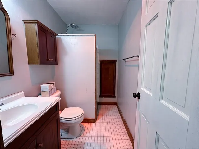 a bathroom with a sink a toilet a mirror and shower