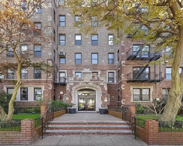 a front view of a brick building next to a yard