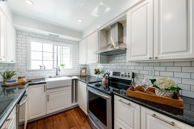 a kitchen with stainless steel appliances granite countertop white cabinets sink stove and granite counter top
