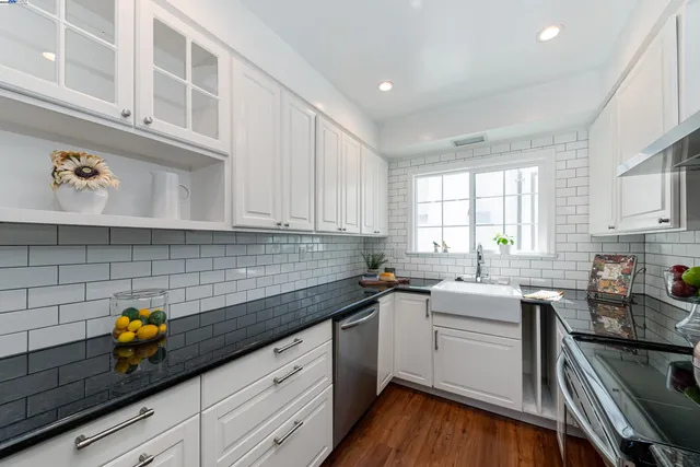 a kitchen with granite countertop stainless steel appliances a sink a stove and cabinets