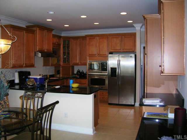 115 Rozelle Valley Lane Cary, NC 27519 - Photo 2 of 6 a kitchen with stainless steel appliances granite countertop a refrigerator a stove a sink a dining table and chairs with wooden floor