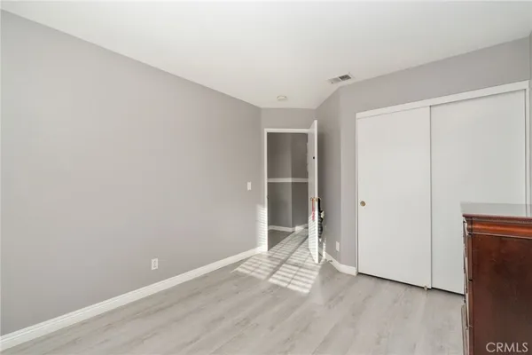 a view of an empty room with wooden floor and closet