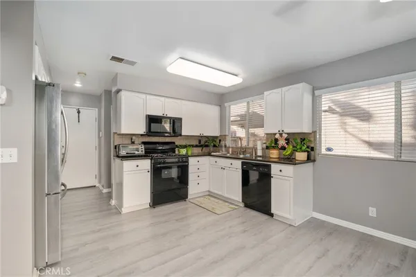 a kitchen with granite countertop stainless steel appliances a refrigerator cabinets and a window