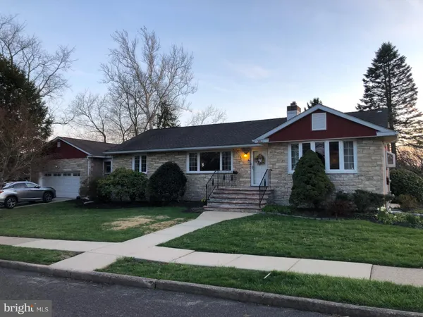 a front view of a house with a garden and trees