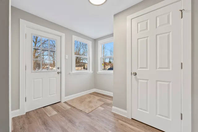 an empty room with wooden floor closet and windows