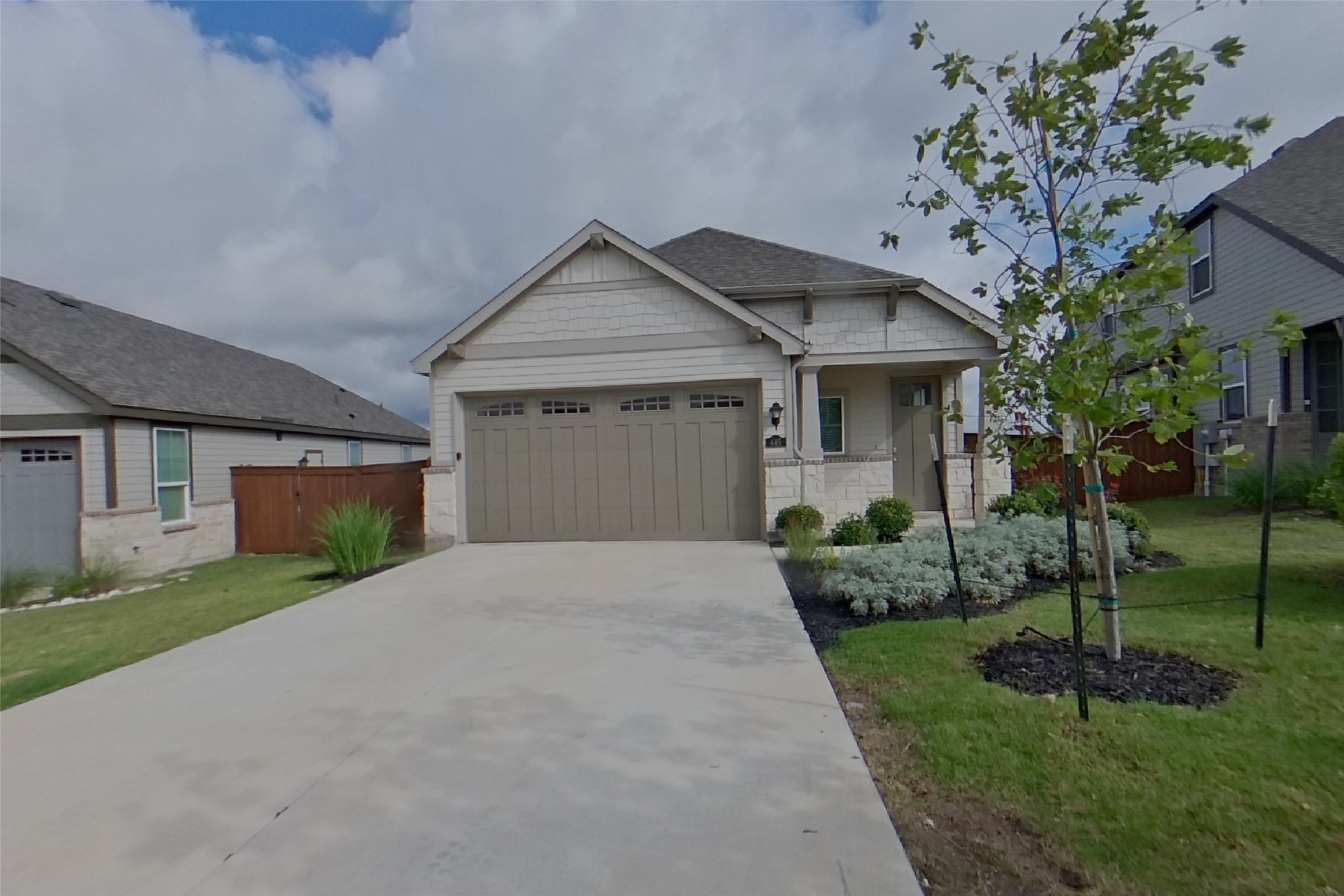 A welcoming facade showcases a broad driveway leading to an integrated garage and a neatly landscaped front yard.