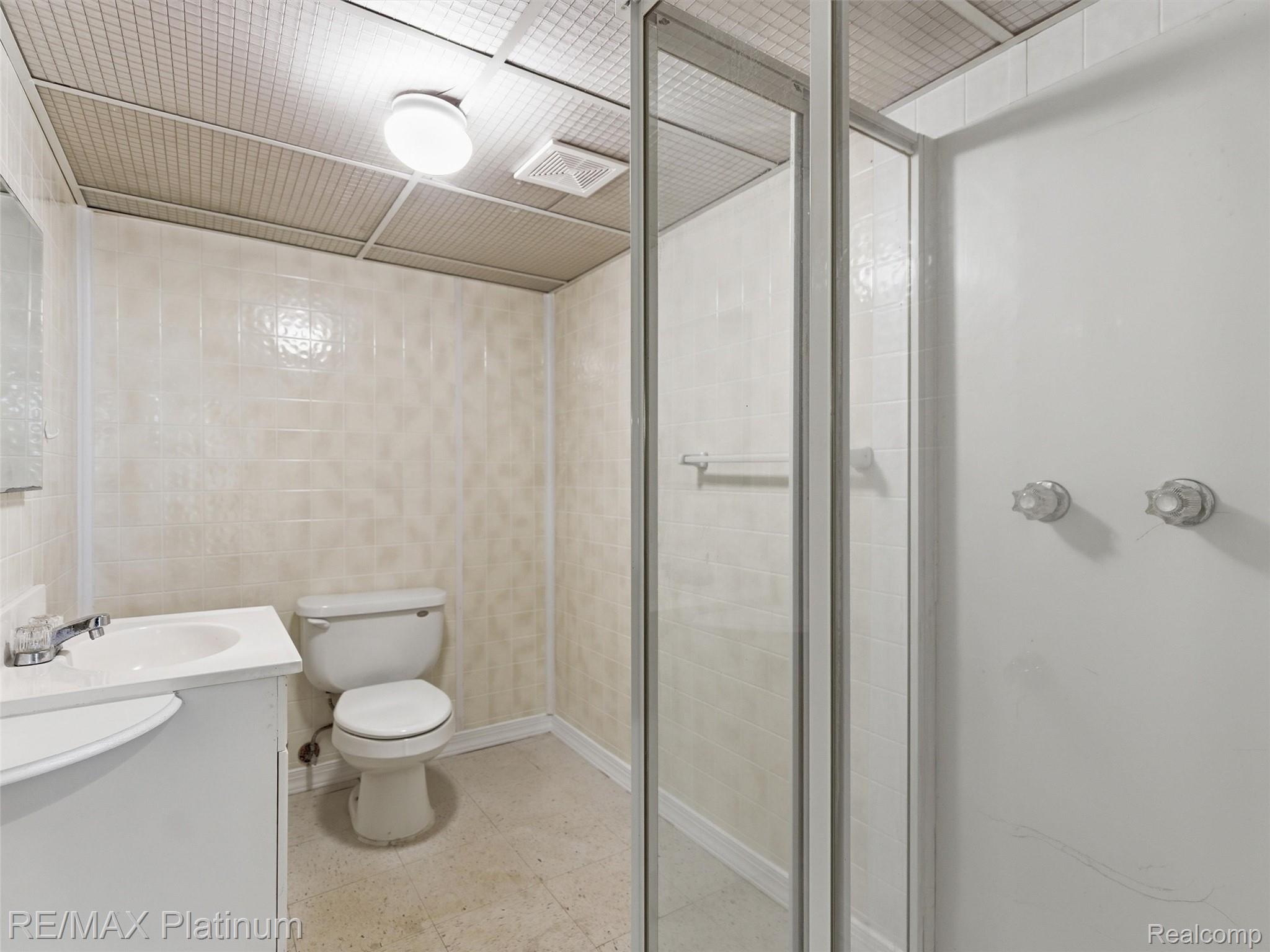 6335 Silver Lake Road Linden, MI 48451 - Photo 36 of 61 Bathroom featuring a white vanity with integrated sink, toilet, and glass-enclosed shower