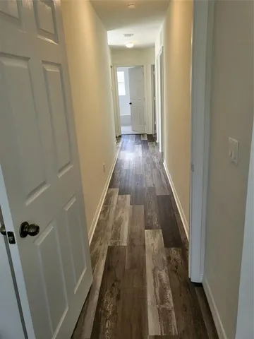 a view of a hallway with wooden floor and a bathroom