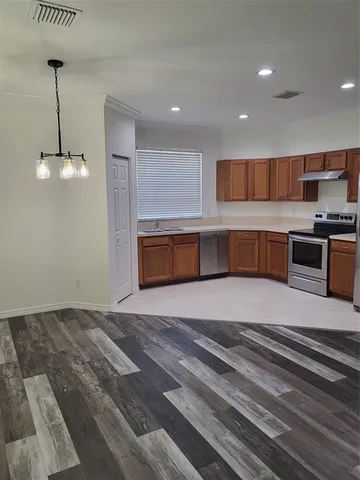 a kitchen with stainless steel appliances granite countertop a sink and stove top oven with wooden floor
