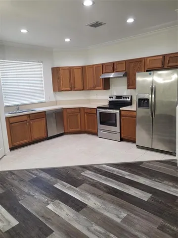 a kitchen with stainless steel appliances wooden cabinets a sink and a stove