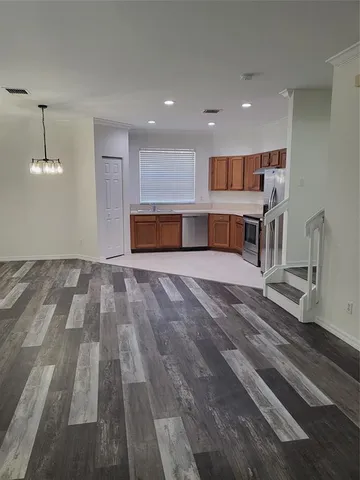 a view of kitchen with stainless steel appliances wooden floor and living room view