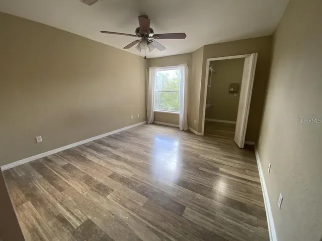 an empty room with wooden floor and a ceiling fan
